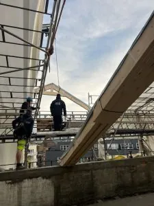 Takarbeidere justerer og monterer stor trekonstruksjon.
