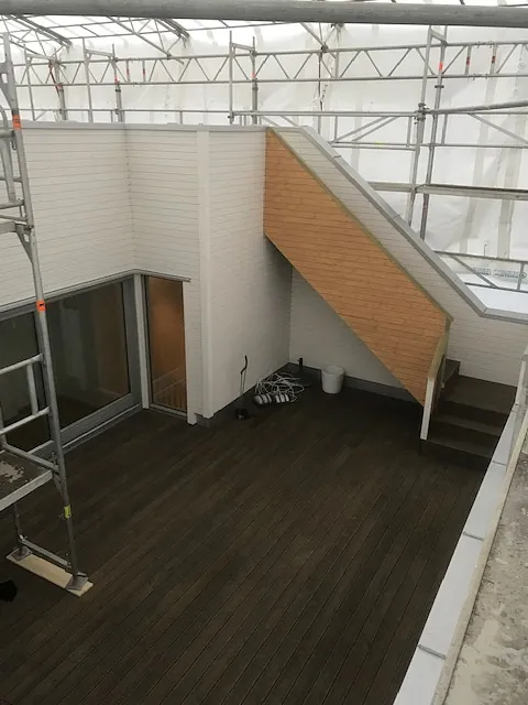 Ferdig uteplass med mørkt tregulv, hvite vegger og trapp.