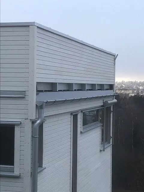 Hvitkledd moderne bygning med takrenner og store vinduer.