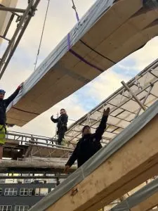 Arbeidere monterer løftet takseksjon under bygging.