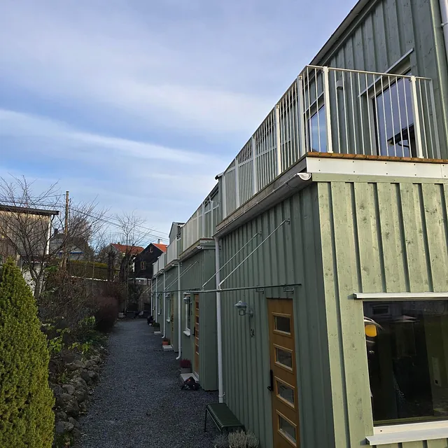 Sideperspektiv av rekkehus med ny balkong og grønn fasade.