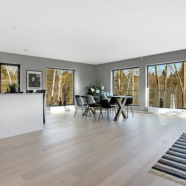 Åpen stue og kjøkken med store vinduer og moderne interiør