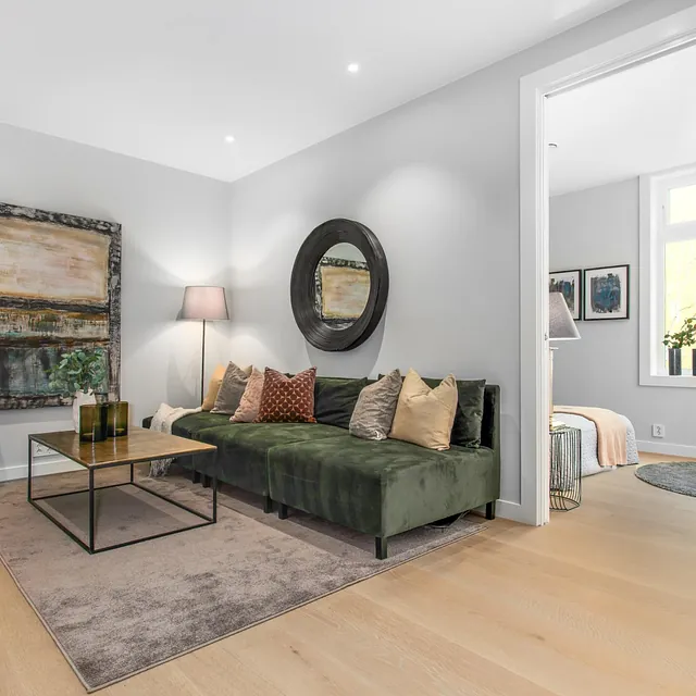 Stue med grønn sofa og store vinduer