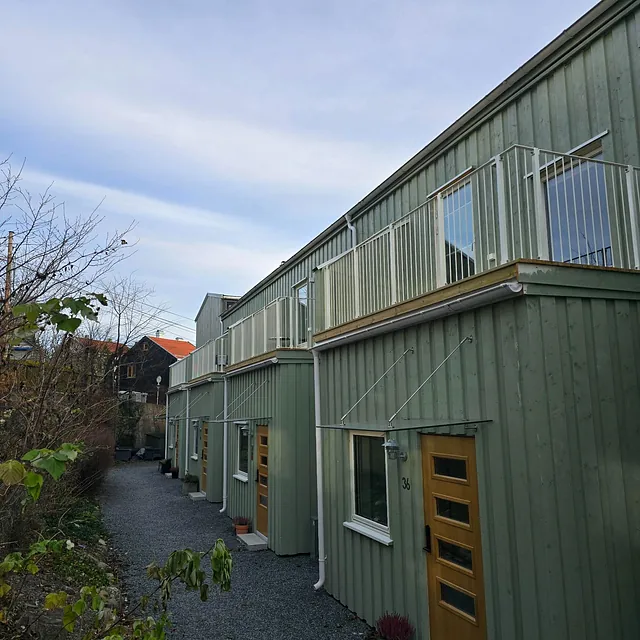 Rekkehus med flere nye balkonger og gruslagt gangvei.