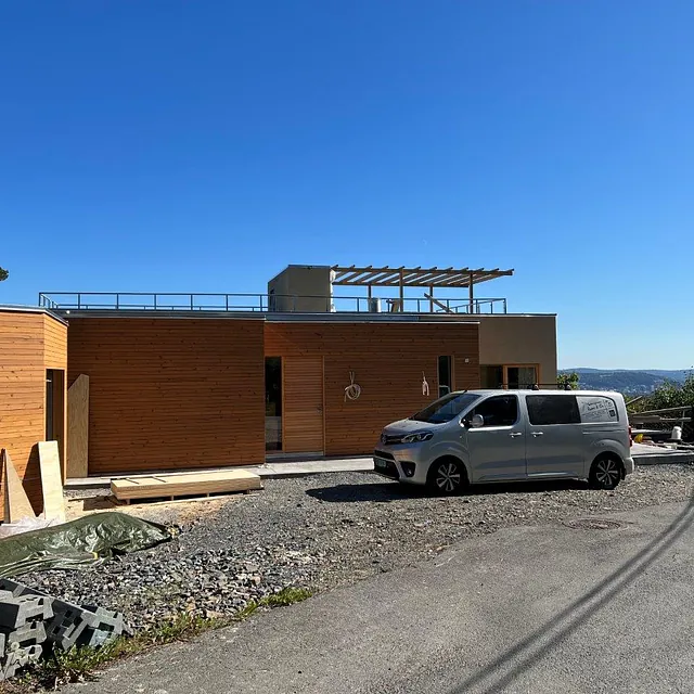 Moderne hus med trekledning og stor takterrasse under oppføring